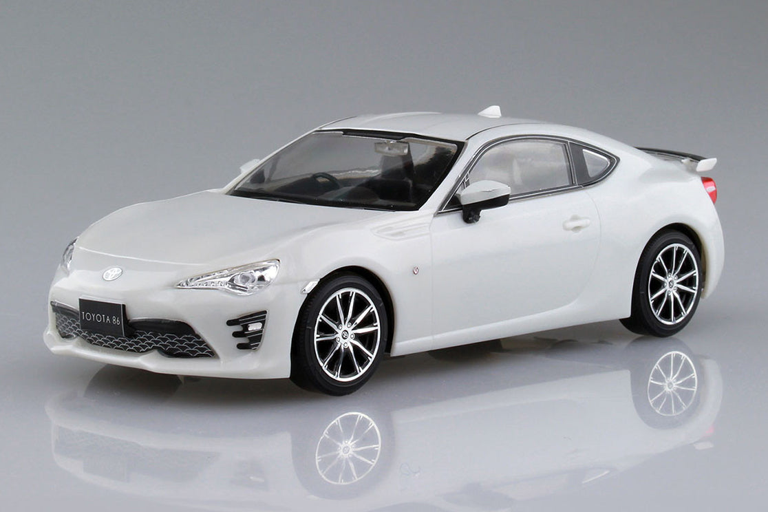 White toy car model on a reflective surface with a gray background