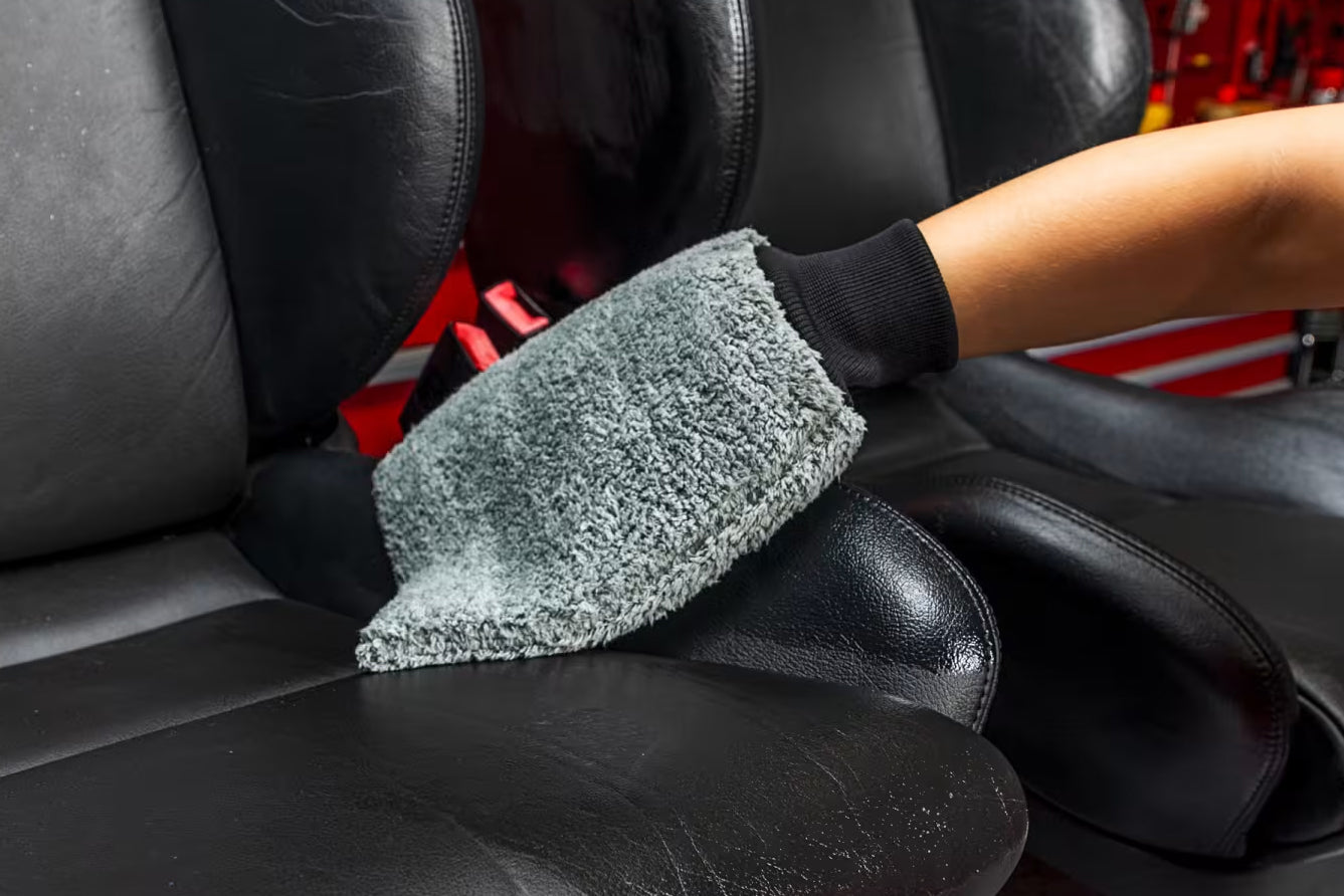 Person cleaning car interior with a microfiber cloth