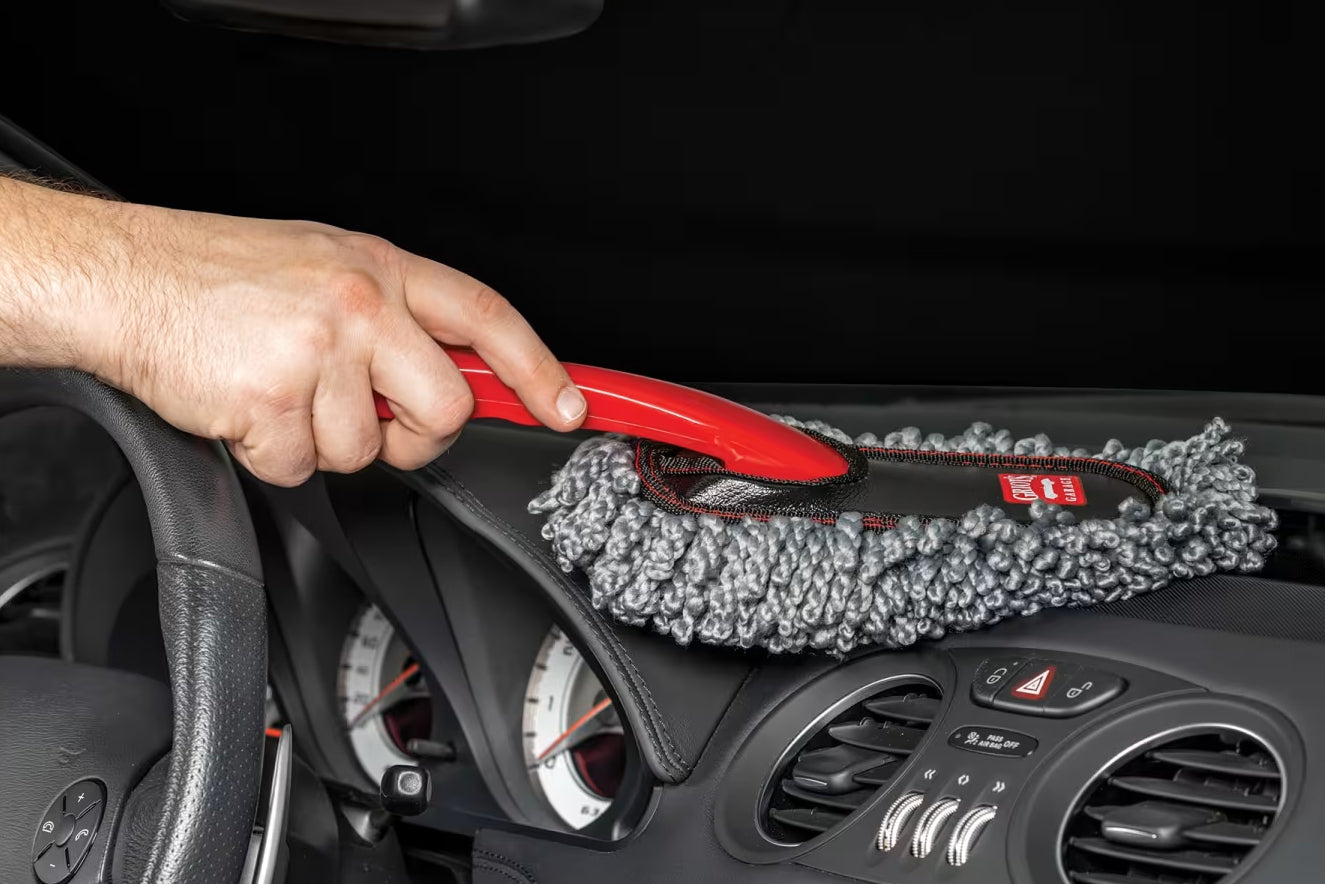 Person cleaning car interior with a microfiber duster