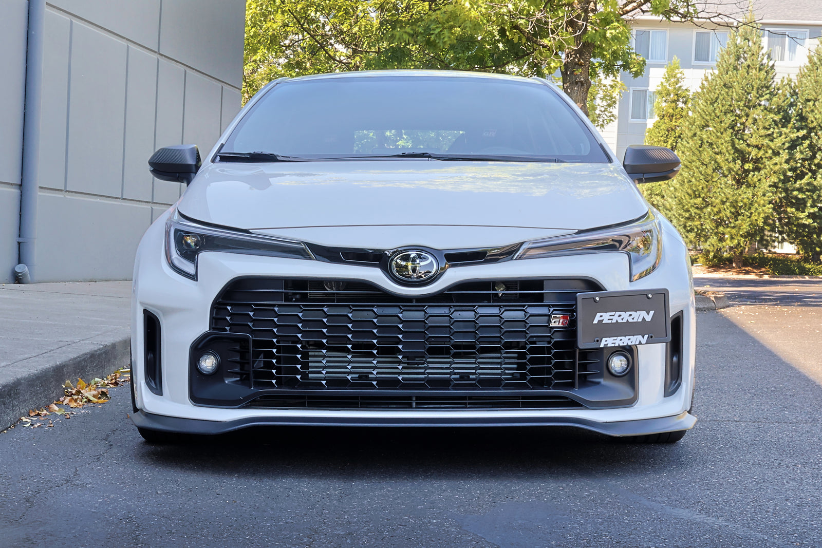 Completed PERRIN License Plate Relocation installation on GR Corolla front bumper showing relocated license plate.