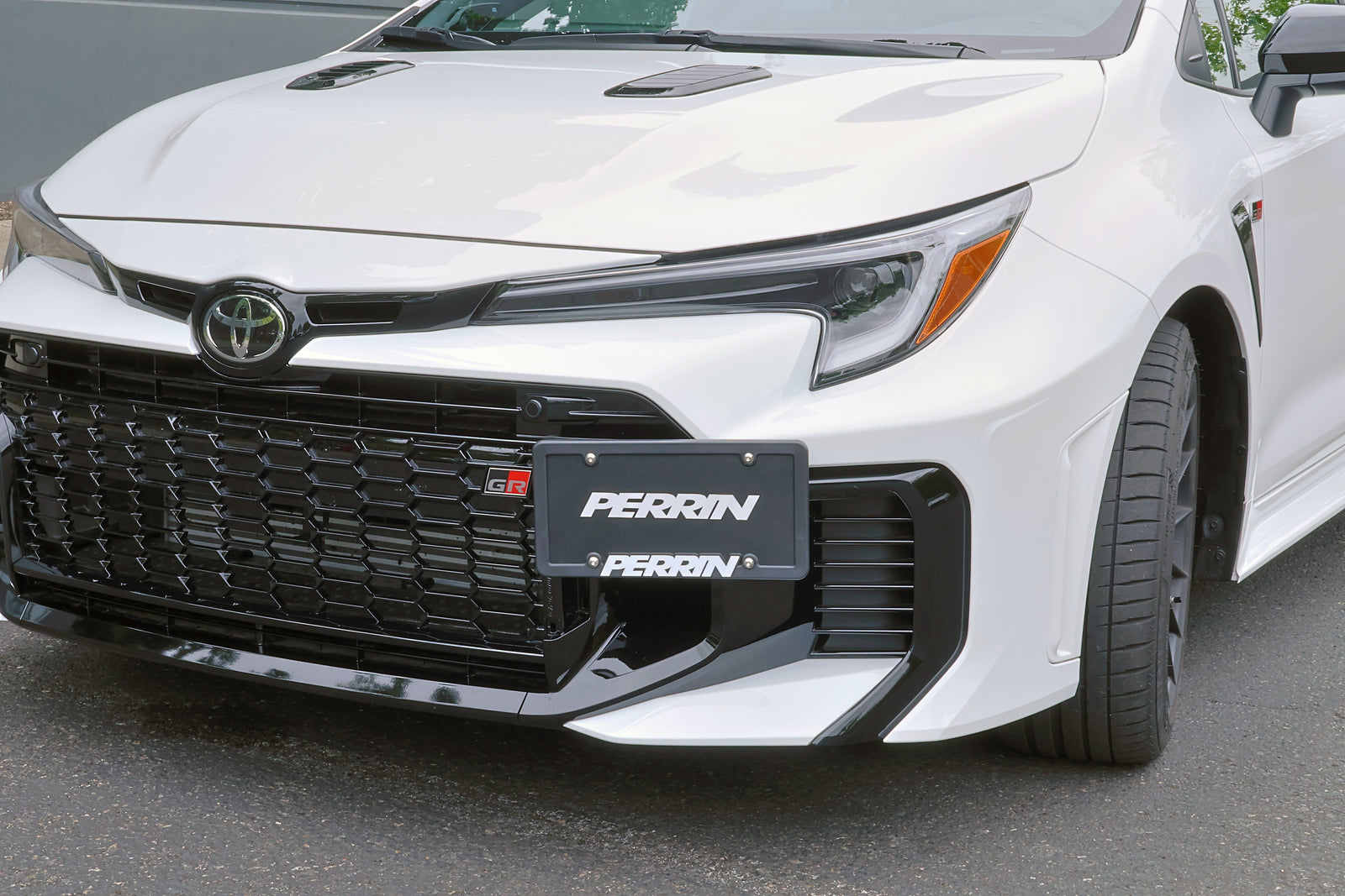 PERRIN license plate relocation installed on white GR Corolla showing finished appearance.