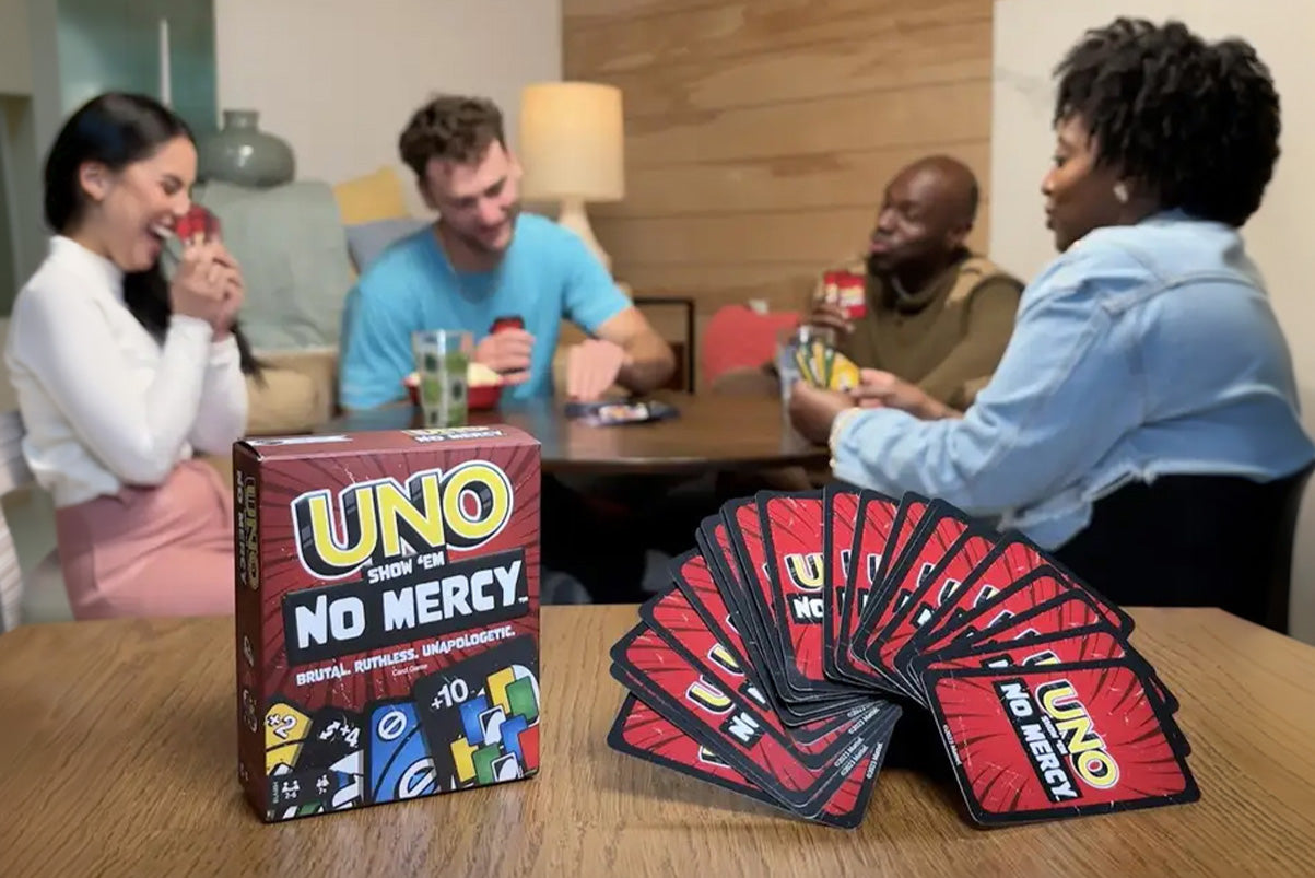 Group of people playing UNO 'No Mercy' card game at a table.