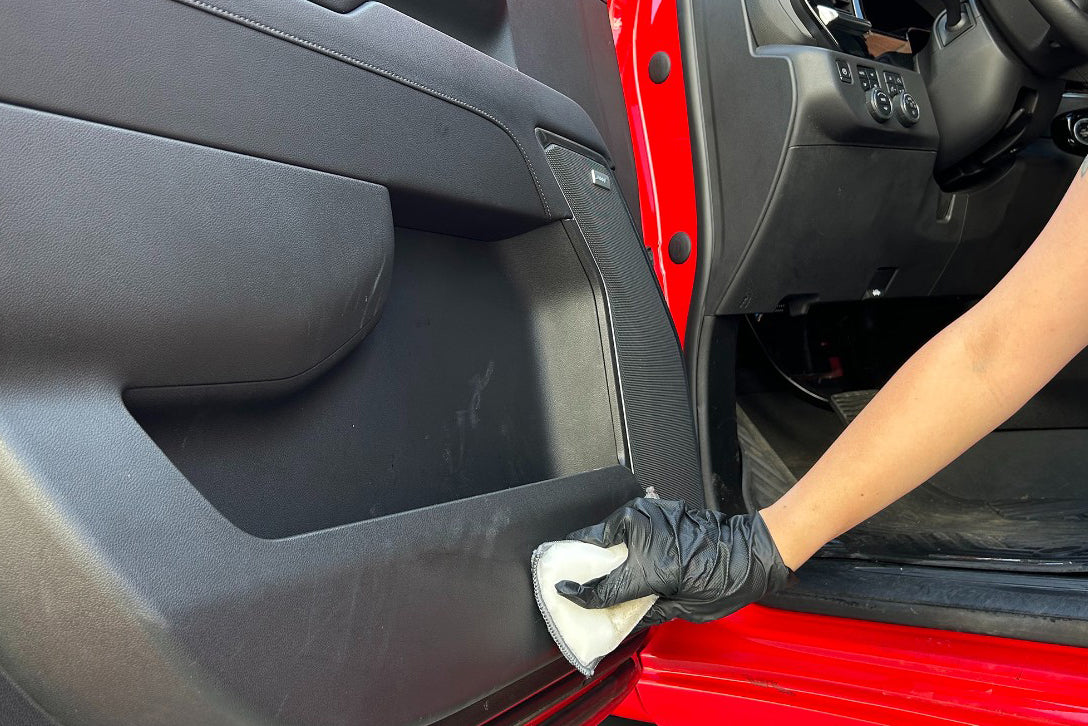 Person cleaning a car's interior panel with a cloth