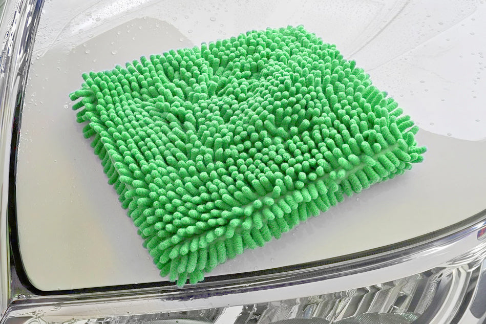 Green microfiber cleaning cloth on a car windshield