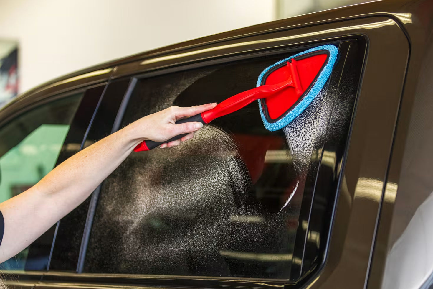 Person cleaning the exterior window on a car