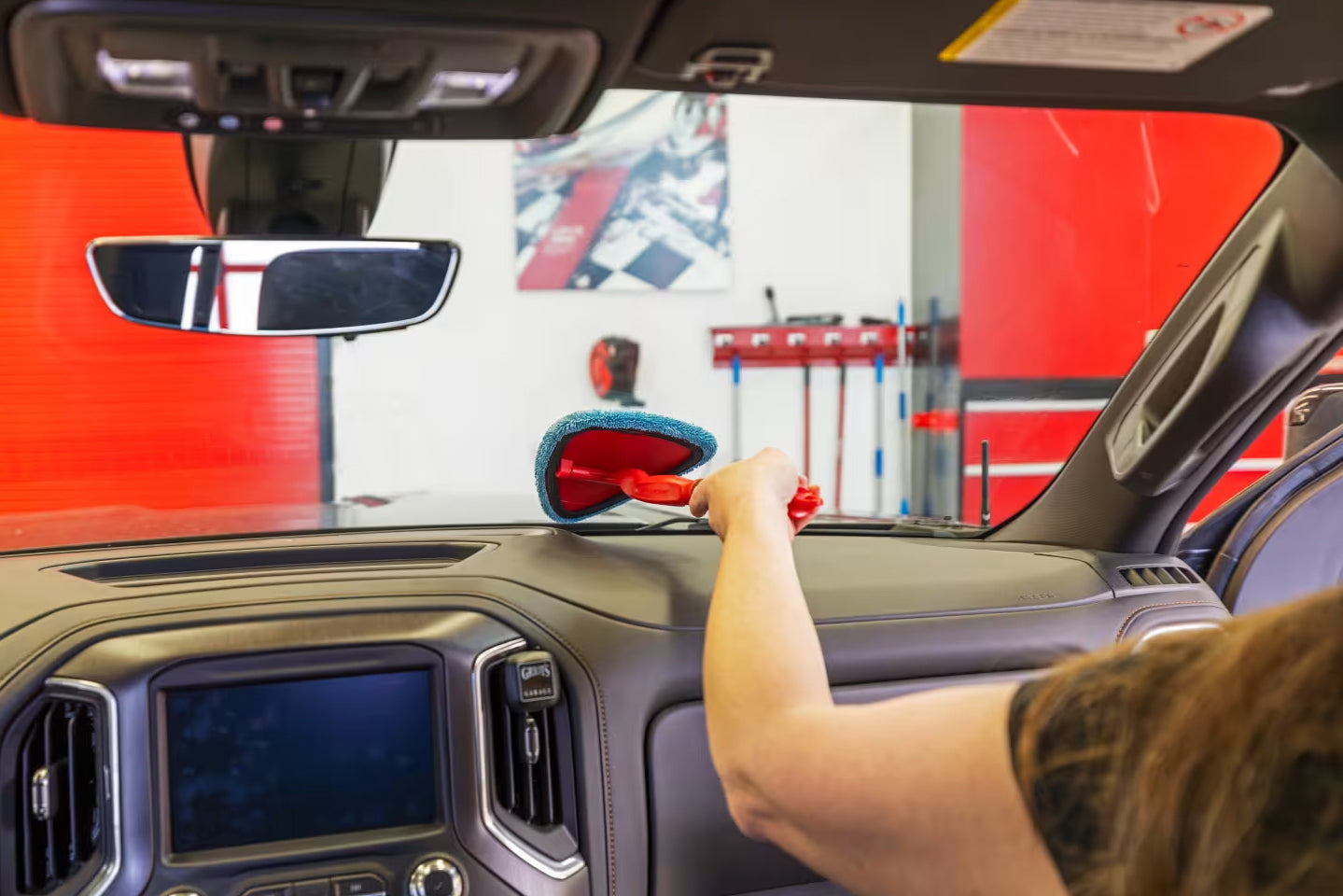 Person dusting the inside of a cars windshield