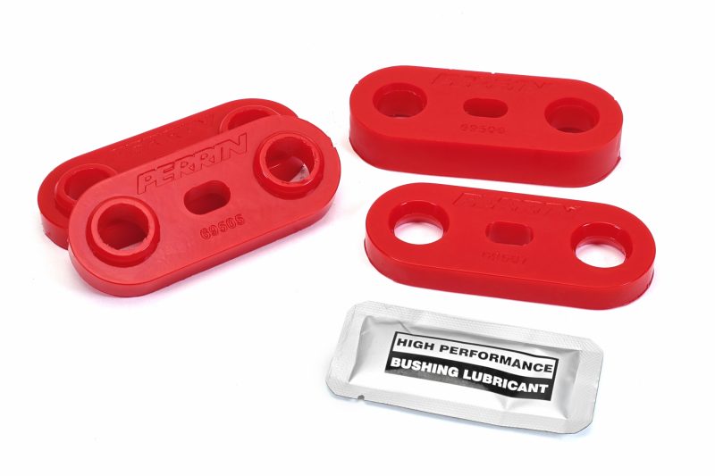 Red transmission crossmember bushings and a packet of high-performance bushing lubricant on a white background.