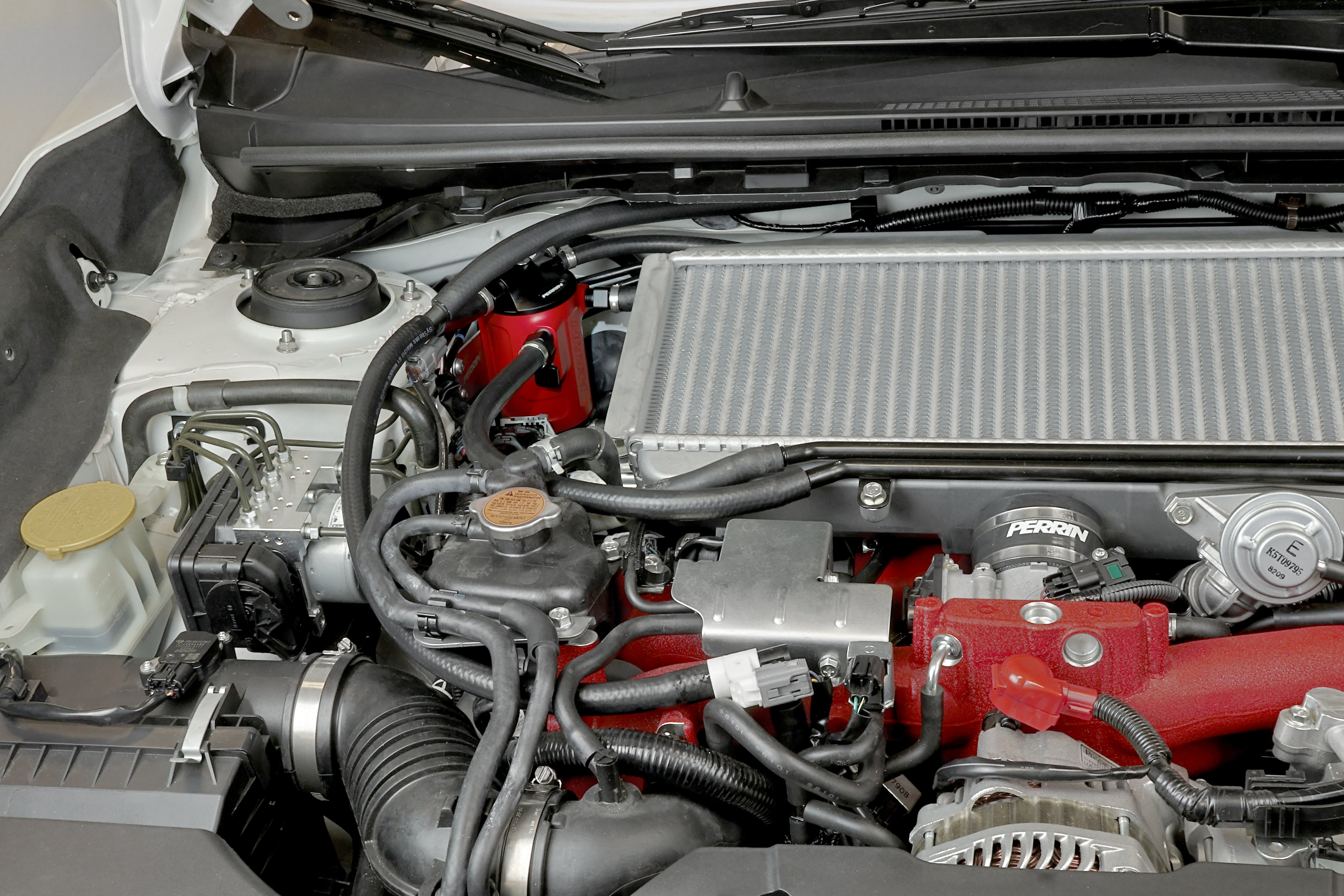 PERRIN red Air Oil Separator installed in 2002-2021 Subaru WRX/STI engine bay.
