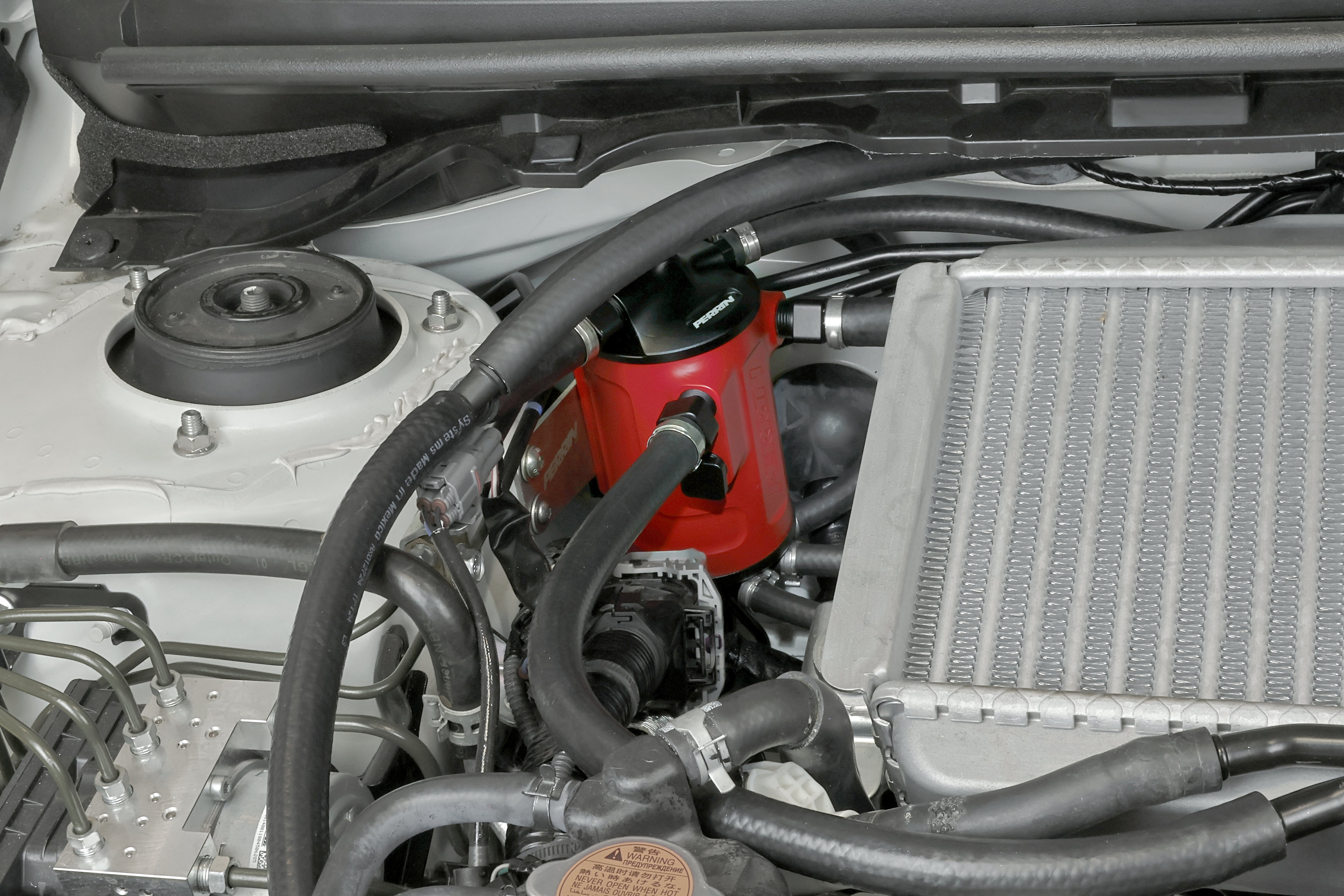 PERRIN red Air Oil Separator installed in 2002-2021 Subaru WRX/STI engine bay.
