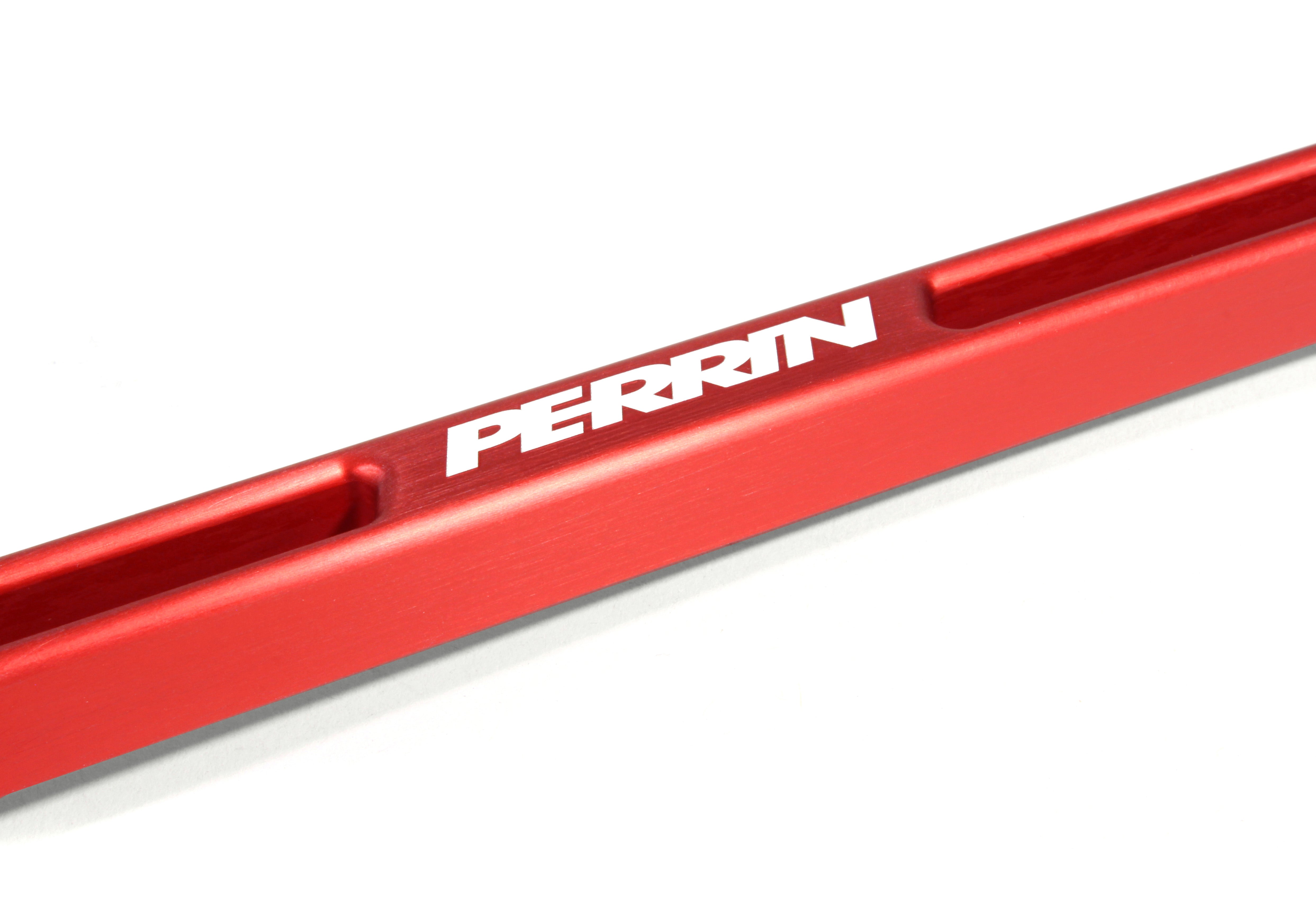 Red aluminum battery tie down with PERRIN branding, designed for performance car enthusiasts.