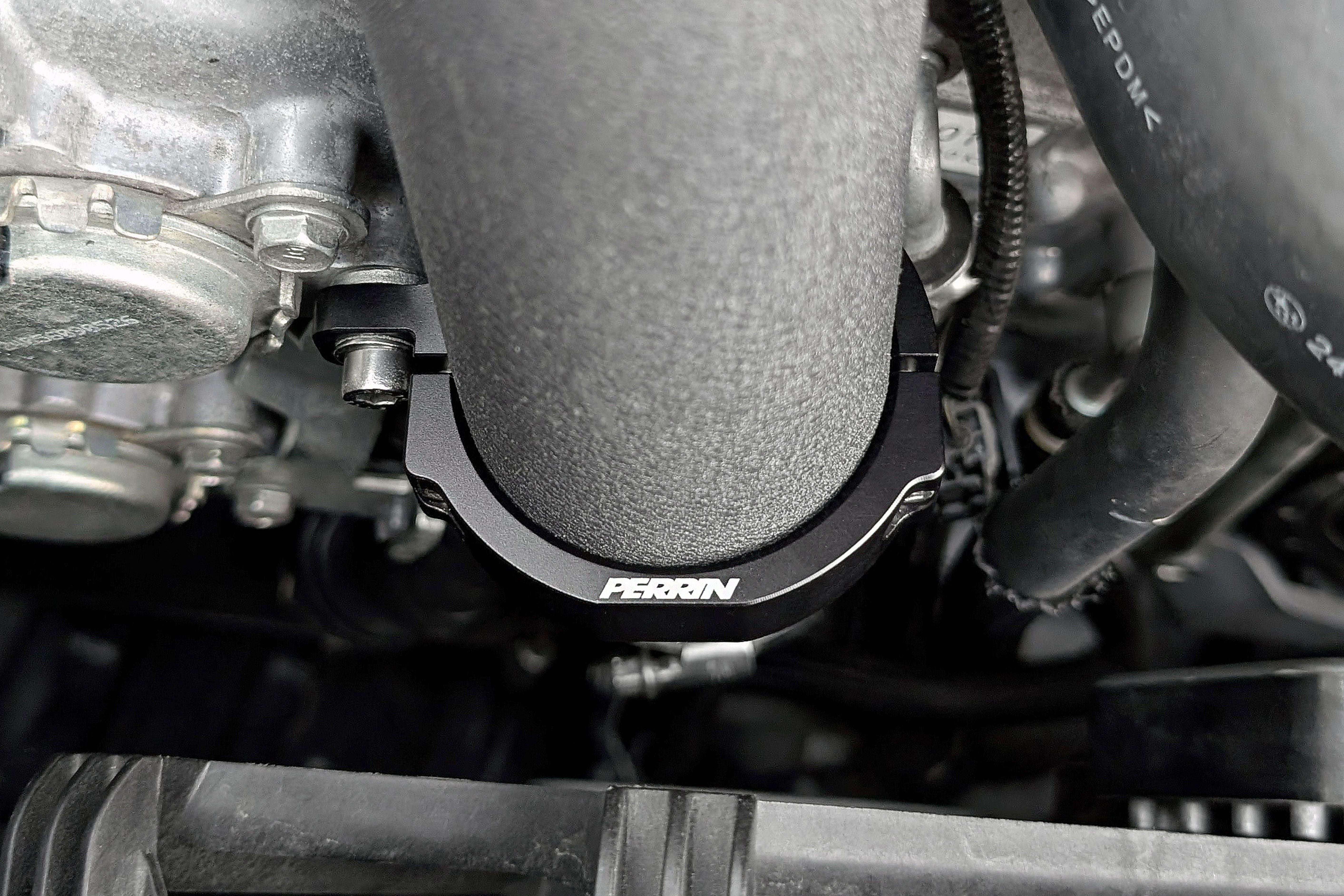 PERRIN Charge Pipe Bracket installed in the engine bay of a Subaru WRX.