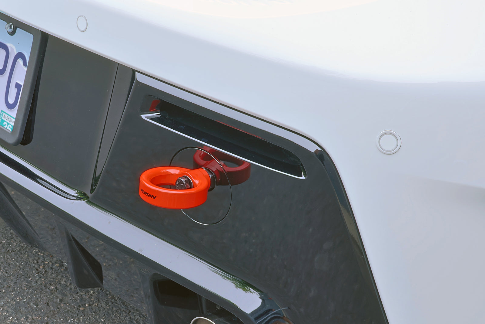 Detail shot of PERRIN red rear tow hook positioned on GR Corolla rear bumper assembly.