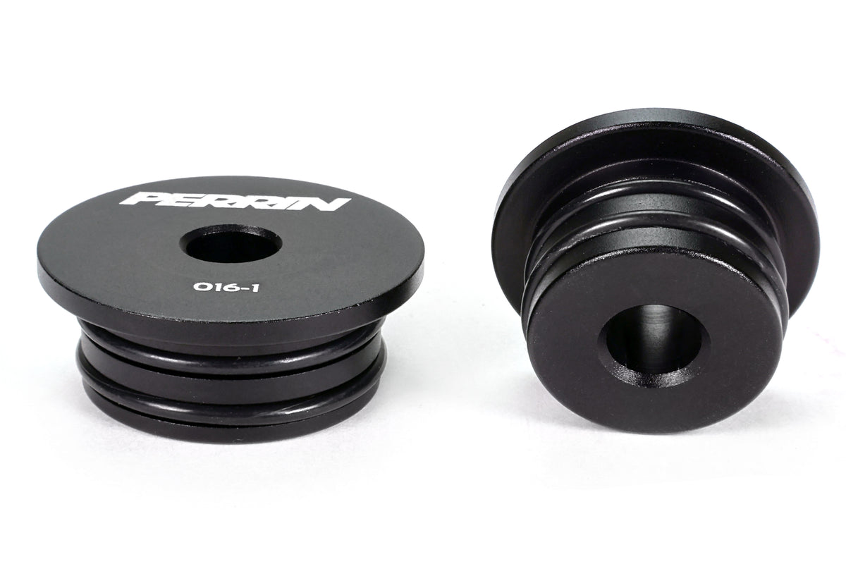 Two PERRIN GR Corolla Shifter Cable Bushings on white background showing top and side faces, black anodized aluminum with engraved PERRIN logo and part numbers.