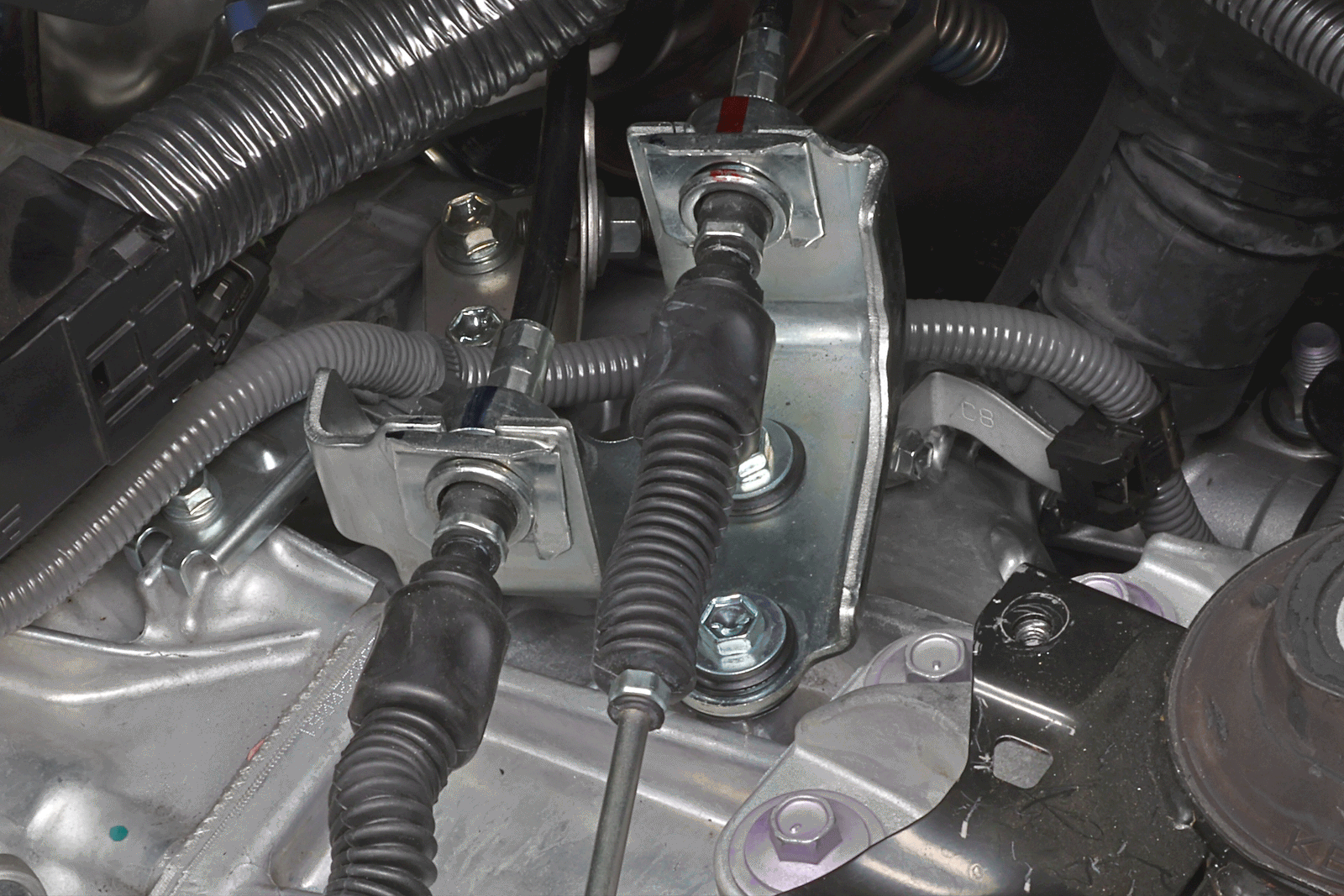 Before and after PERRIN GR Corolla Shifter Cable Bracket Lockdown with a black anodized installed on a Toyota GR Corolla.
