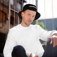 A model wearing a black bucket hat with the Perrin logo, paired with a white sweatshirt, against an urban backdrop.