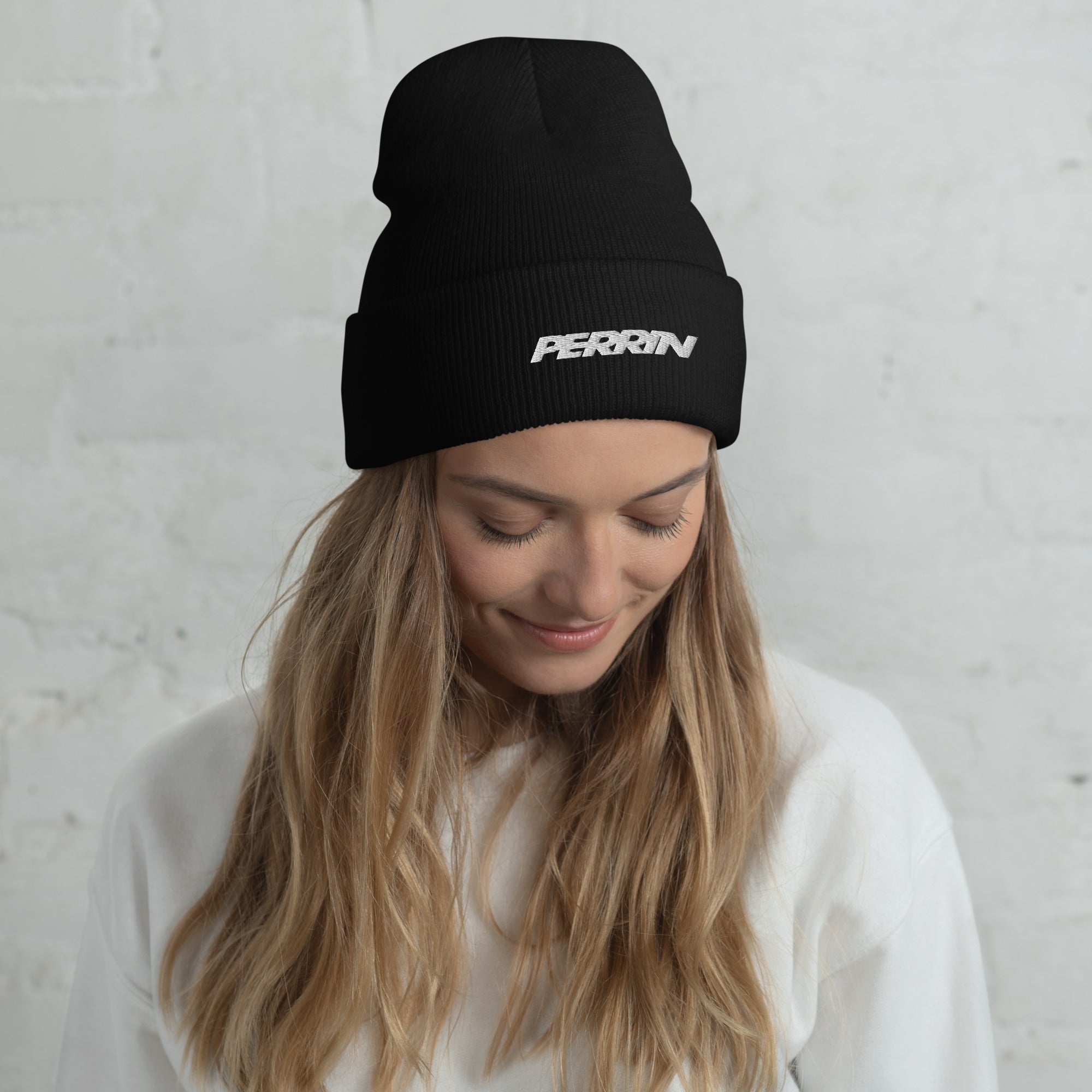Black cuffed beanie featuring the Perrin logo, worn by a woman with long hair, set against a neutral background.